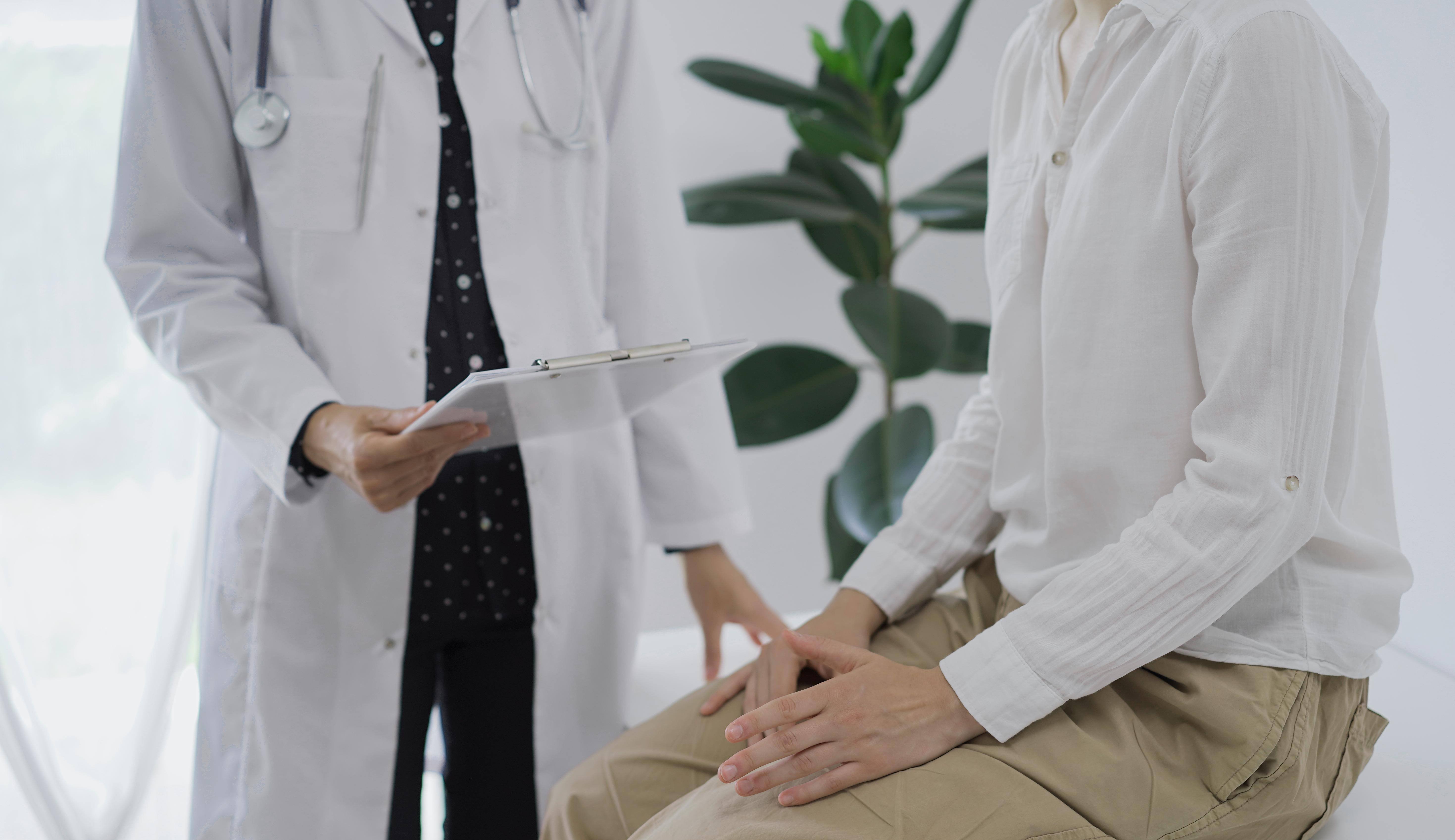 A doctor engages in conversation with a patient, discussing health concerns in a clinical setting.