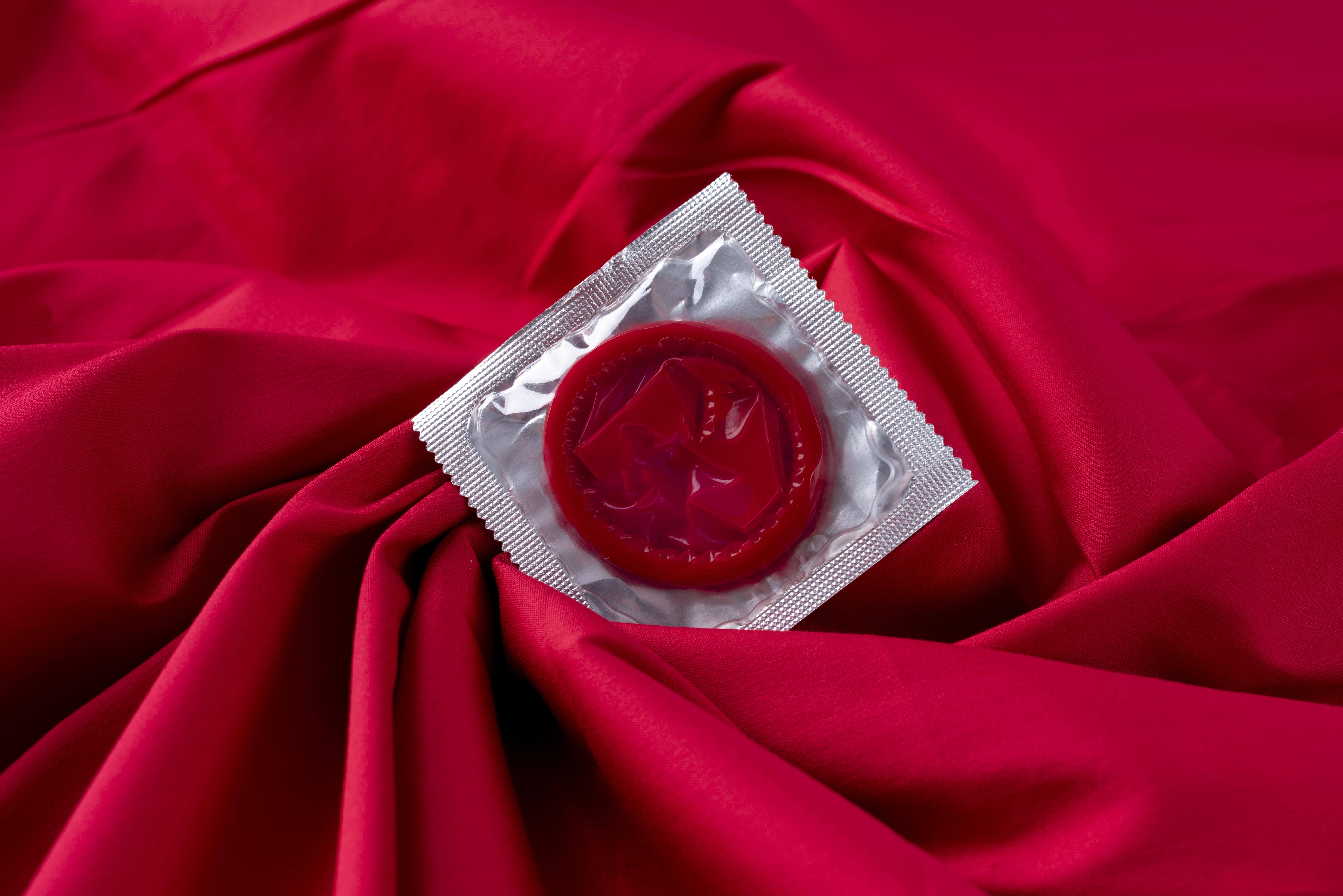 A condom placed on a vibrant red cloth, highlighting its smooth texture and color contrast.